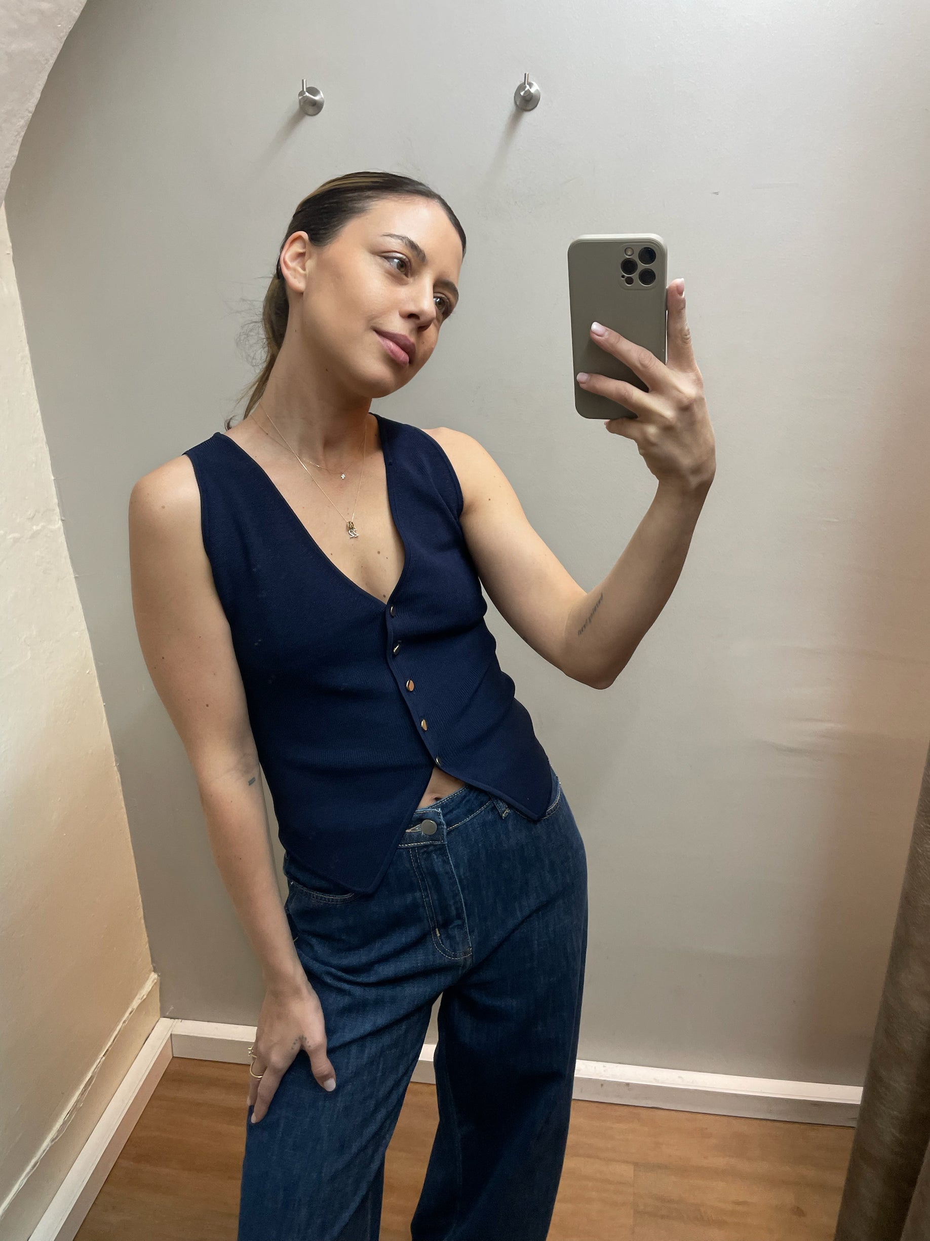 Elegante dunkelblaue Strickweste mit Knopfleiste und tiefem V-Ausschnitt an Model getragen, minimalistischer Luxus Boutique Stil